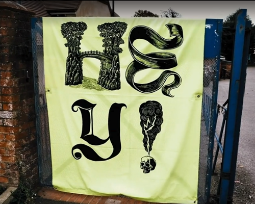 A picture of the 'Hey!' banner in yellow with black text on a railing